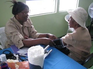 En äldre dam får blodtrycket mätt under en hälsodag i Albouystown.